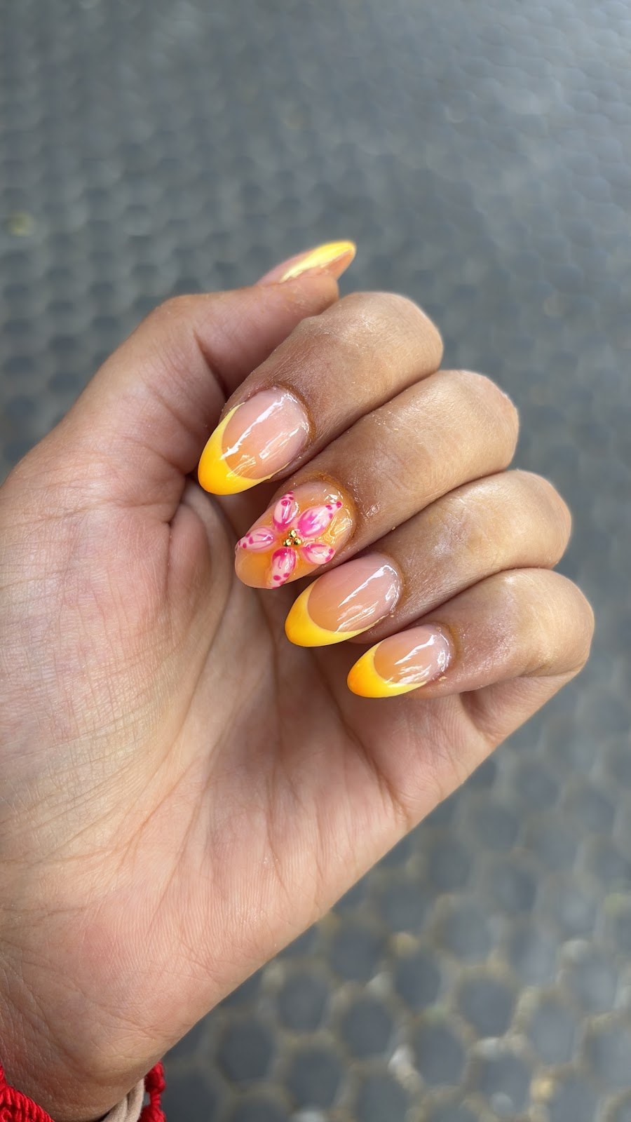 Uñas con la punta naranja y una flor pintada en una de ellas