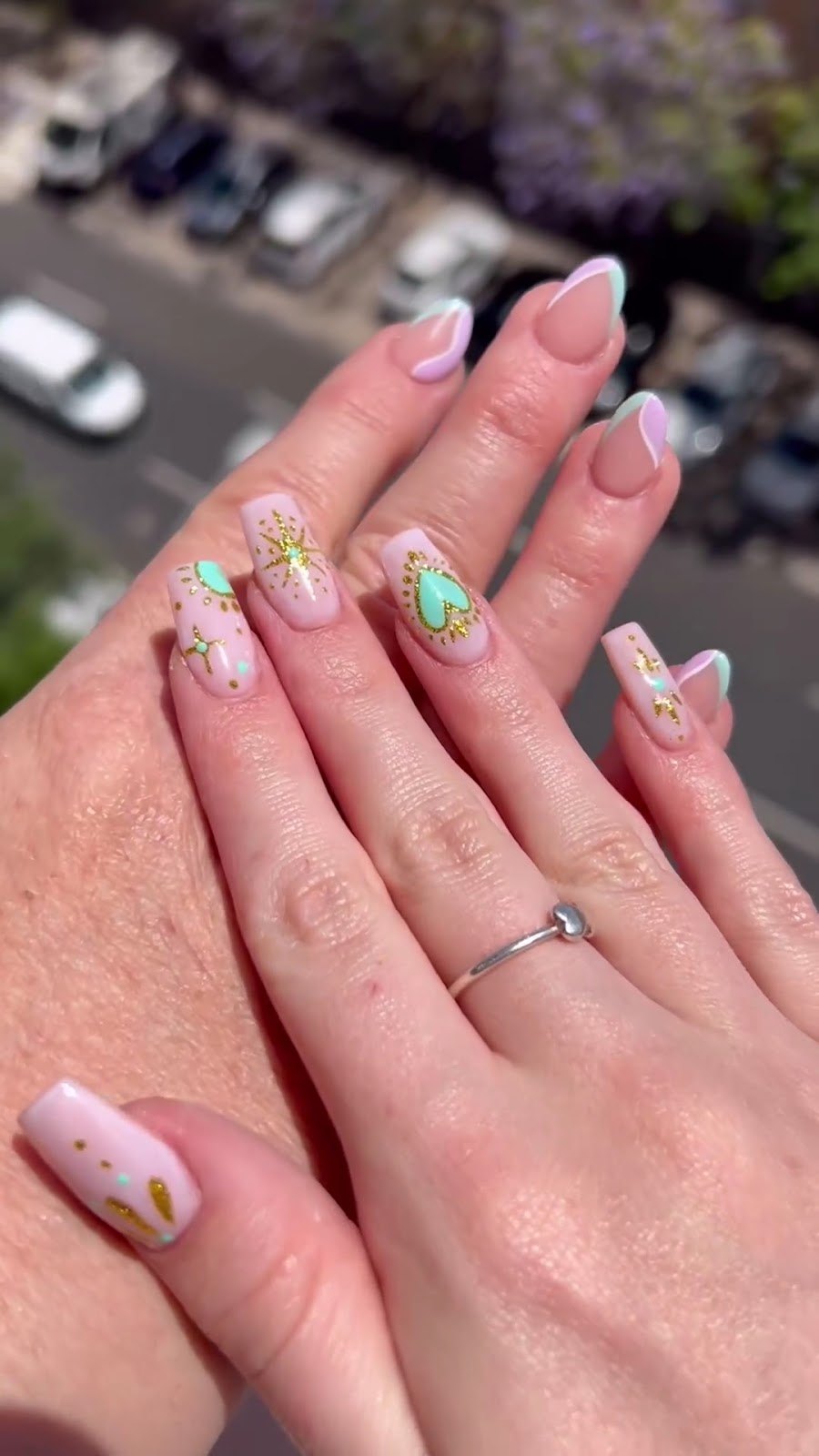 Uñas cortas rosa pastel con corazones verdes y detalles dorados