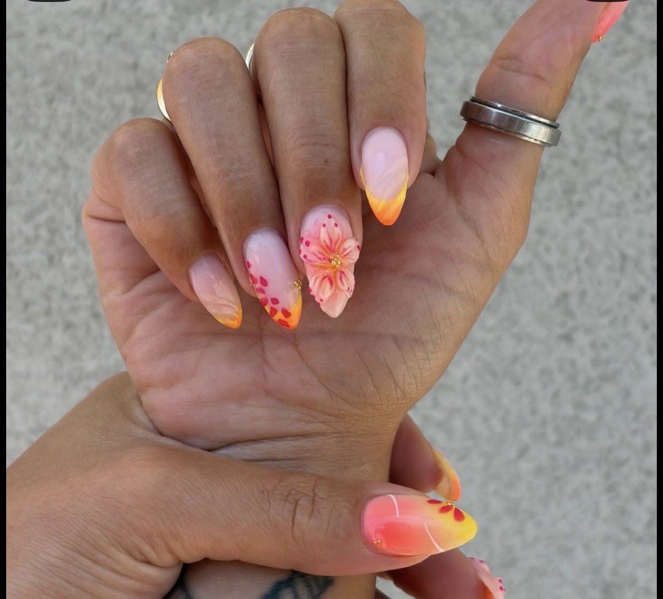 Uñas almendradas con degradado naranja y una flor pintada en relieve