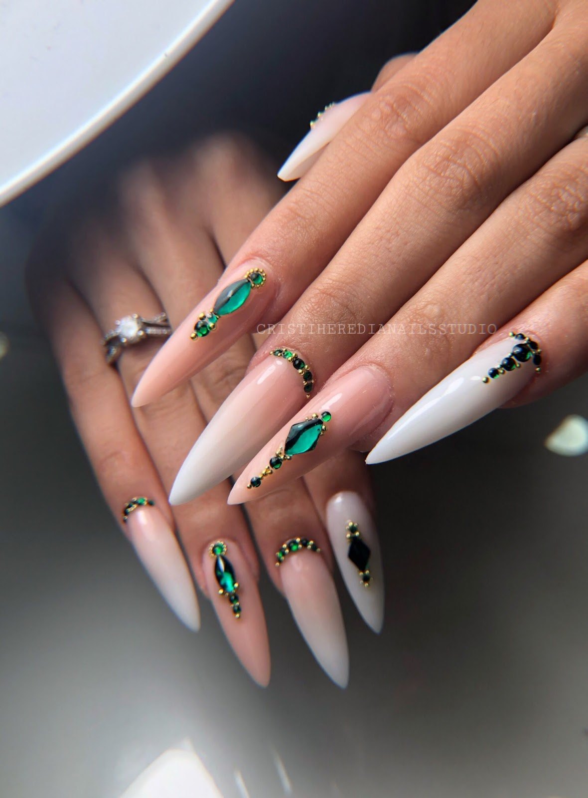 Uñas largas en punta, de color nude con piedras verdes engastadas